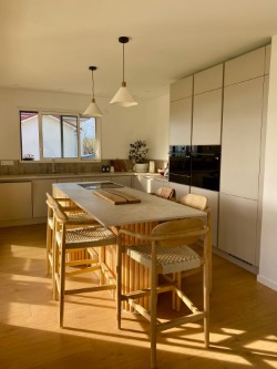 Cuisine beige baignée de soleil avec grand îlot et tabourets